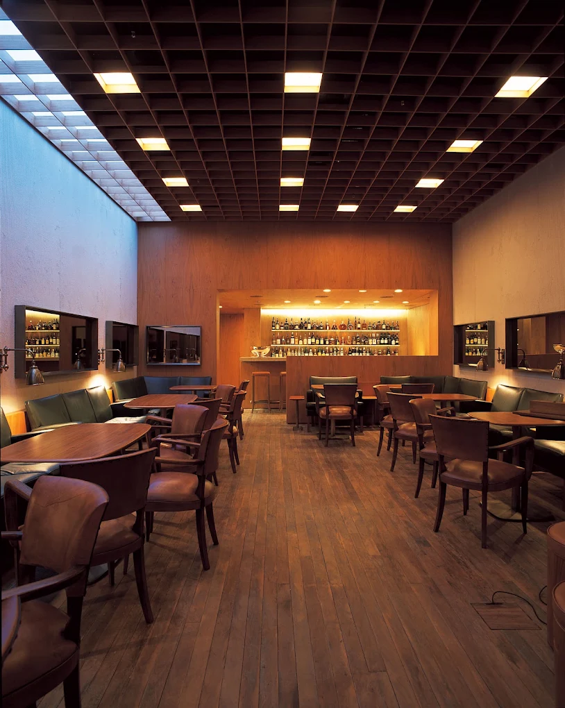 Salão do Baretto Fasano com bar iluminado e piano de cauda
